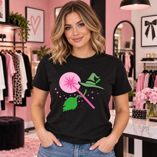Pink wand and witch essentials design on black T-shirt model